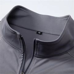 Close-up of a gray jacket with a zipper and brand logo on a light gray background