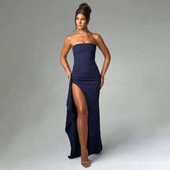 Woman wearing a strapless navy gown with a high slit on a gray background