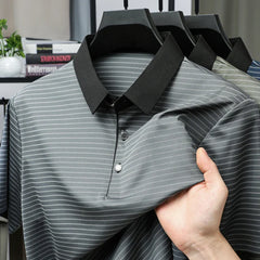 Gray striped polo shirt with black collar held by a hand on a blurred background