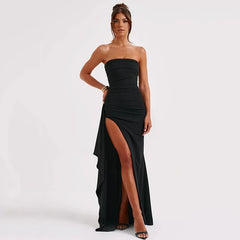 Woman wearing a black strapless gown with a high slit on a white background